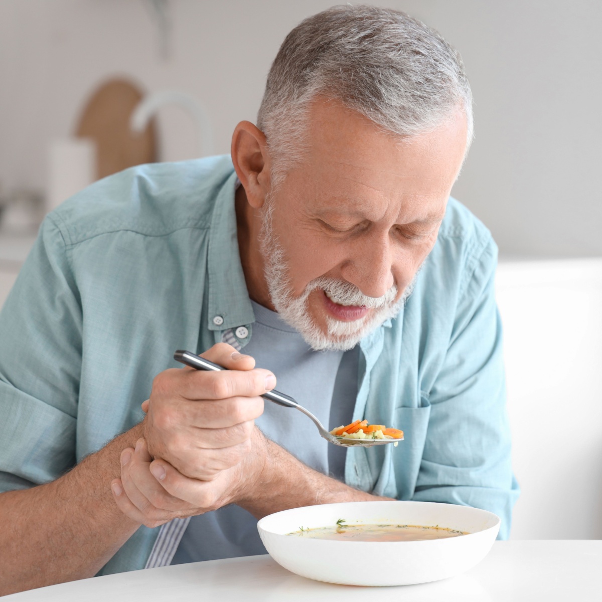 older man eating a bowl of soup