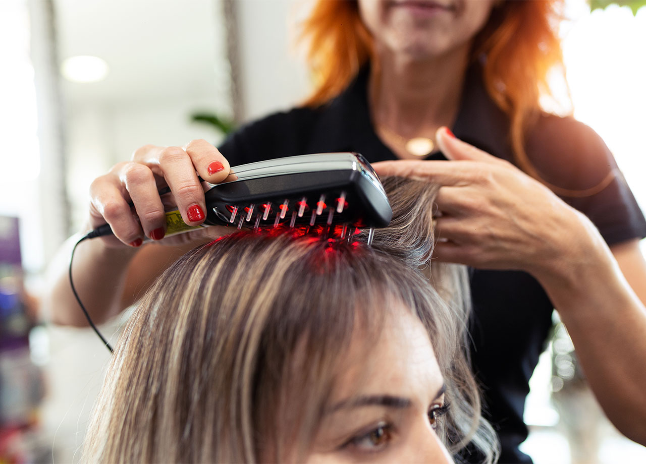 close up of hairdresser doing a treatment with ultrasonic and infrared laser comb for hair regrowth