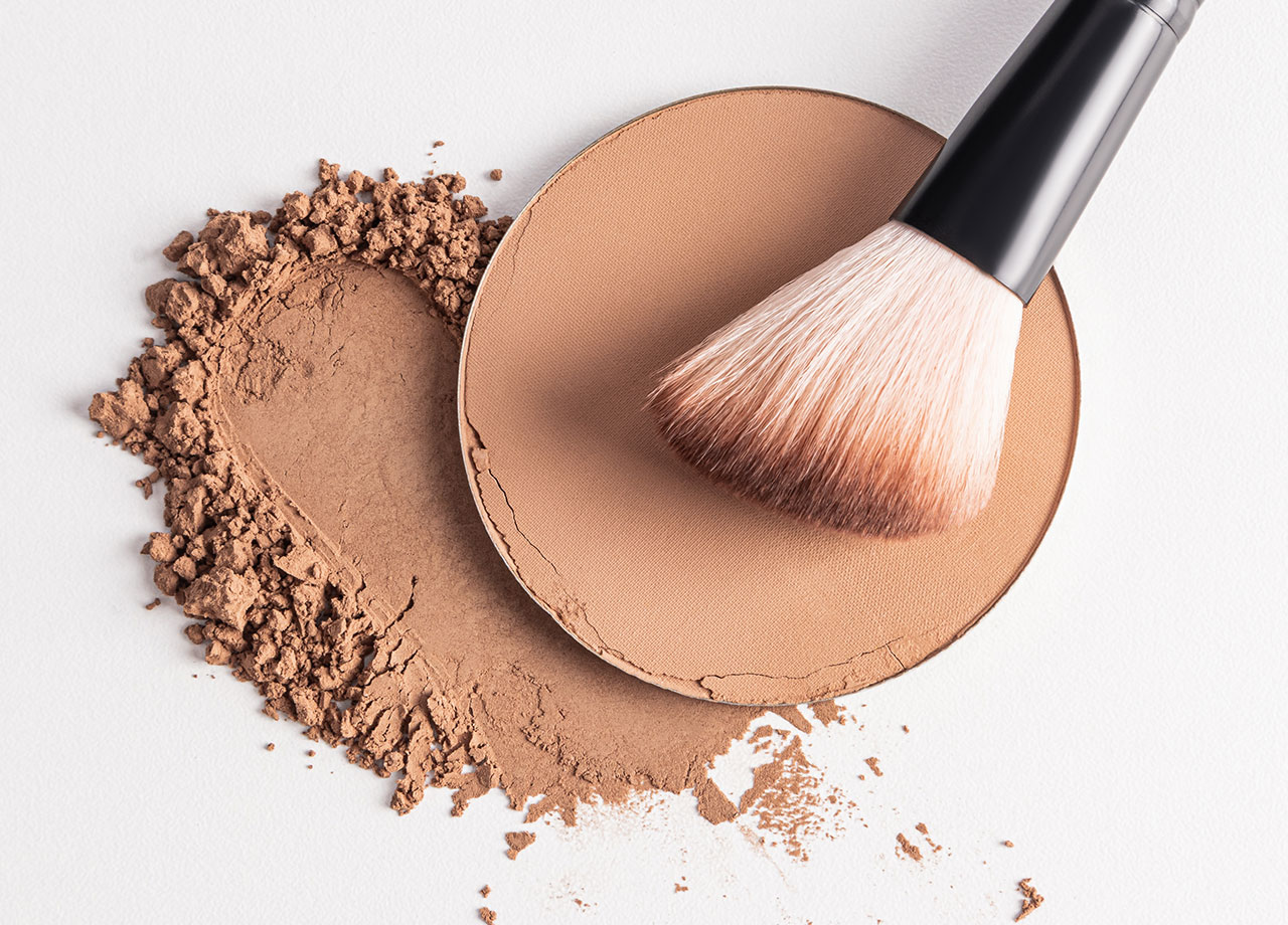 pot of powder foundation makeup with a brush