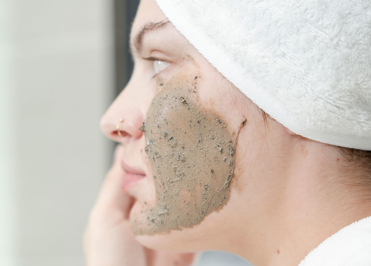 woman using an exfoliating scrub facial mask