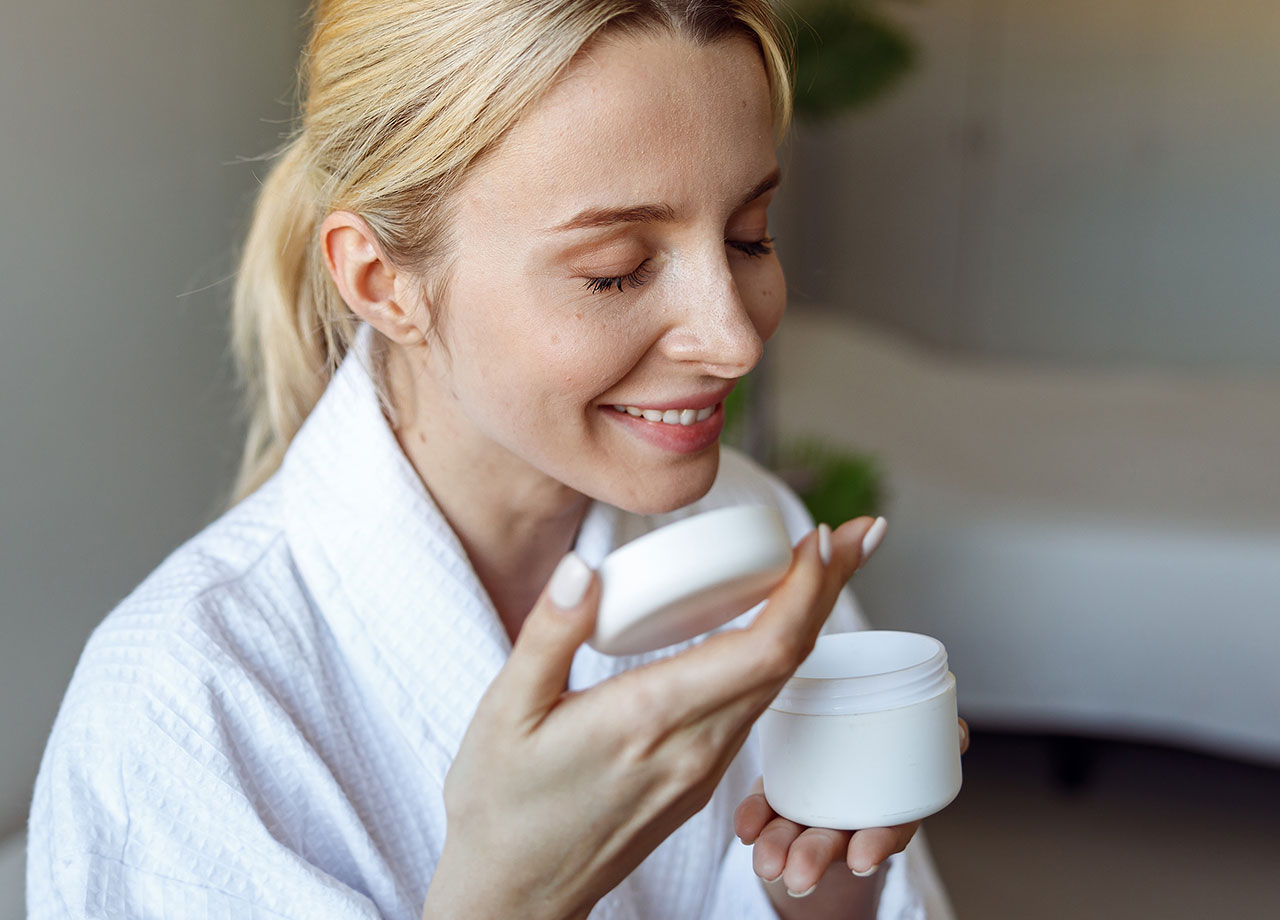 women sniffing a jar of scented moisturizer