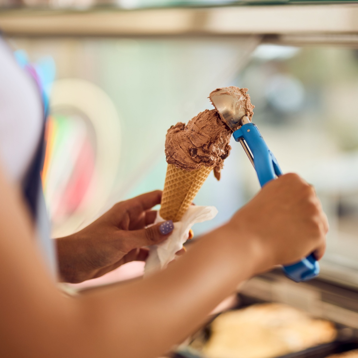 person scooping ice cream on cone