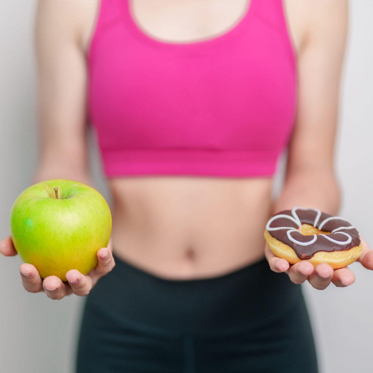 fit woman holding apple and donut