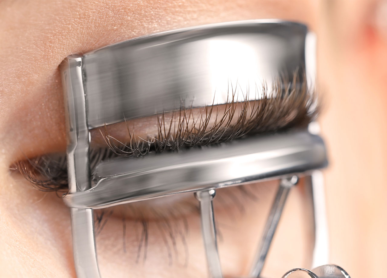 woman-curling-eyelashes