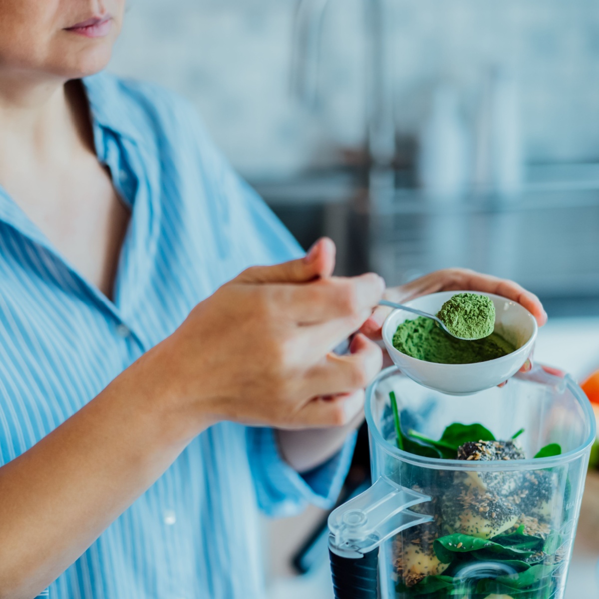 woman adding plant based protein to smoothie