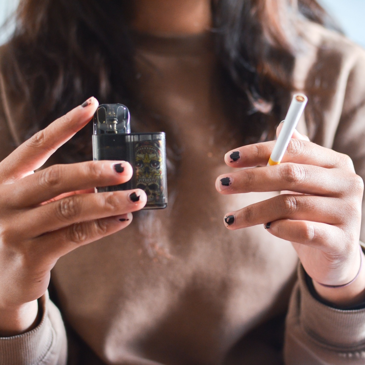 woman holding a vape and cig