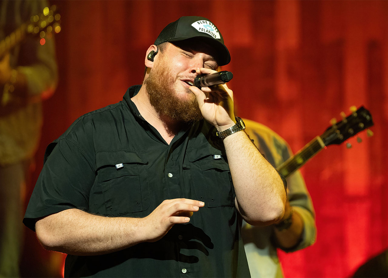 luke combs performing onstage microphone hat black shirt