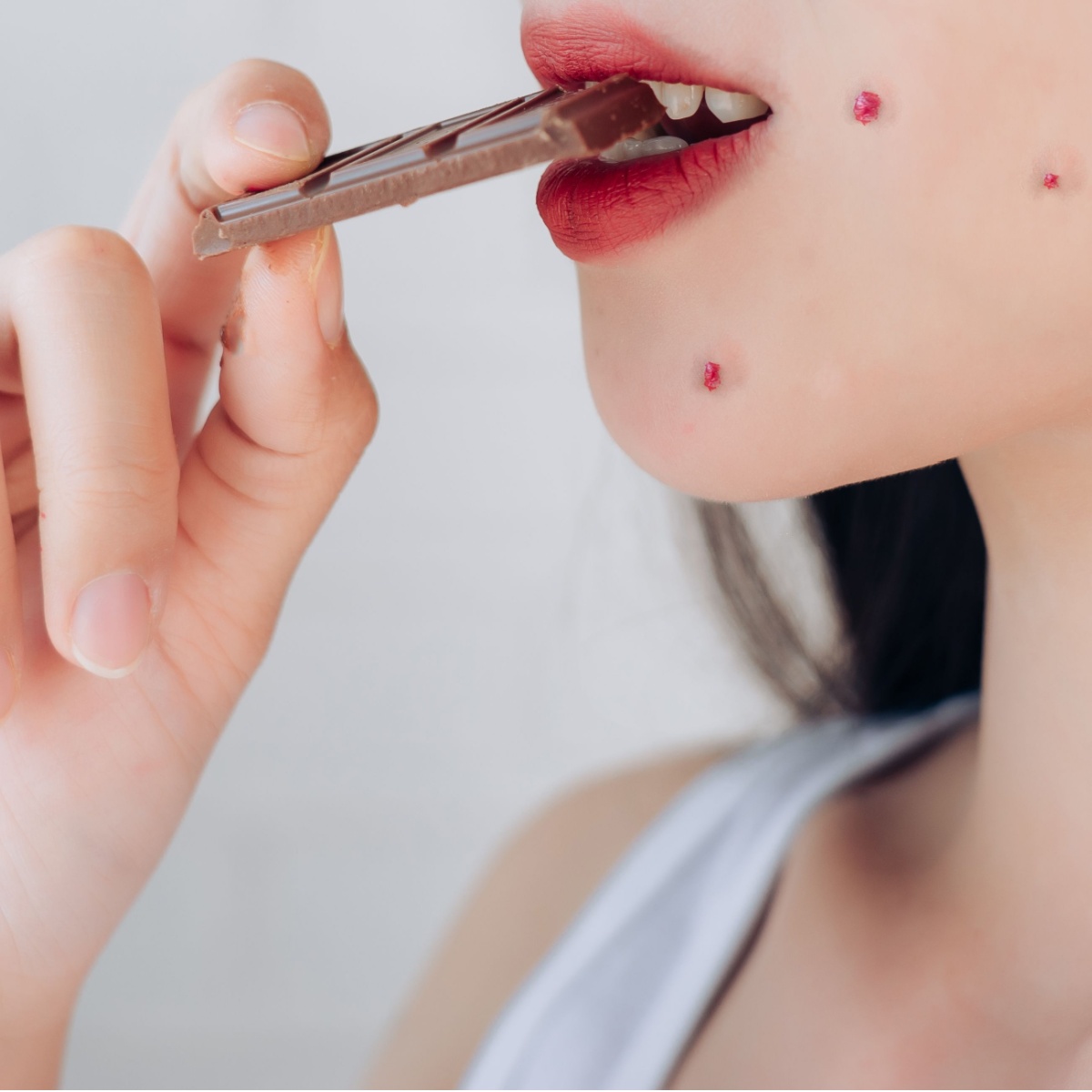 woman with acne eating chocolate