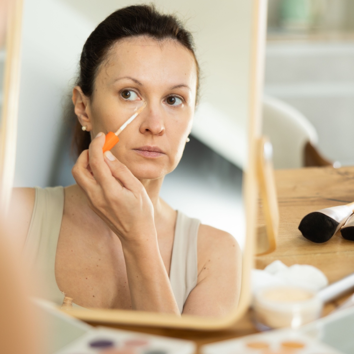 older woman using concealer