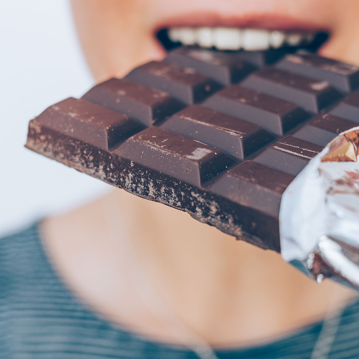 woman biting into dark chocolate bar