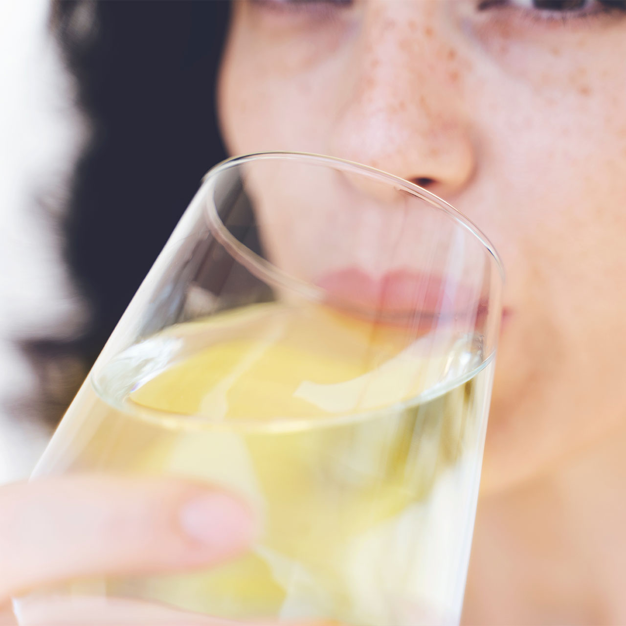 woman drinking white wine from glass