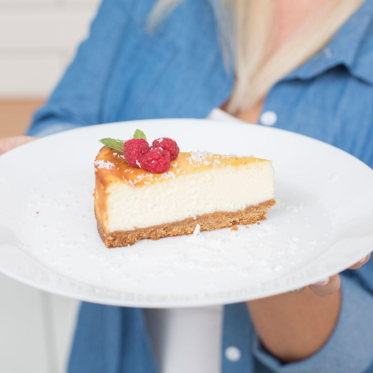 woman holding up a plate of cheesecake