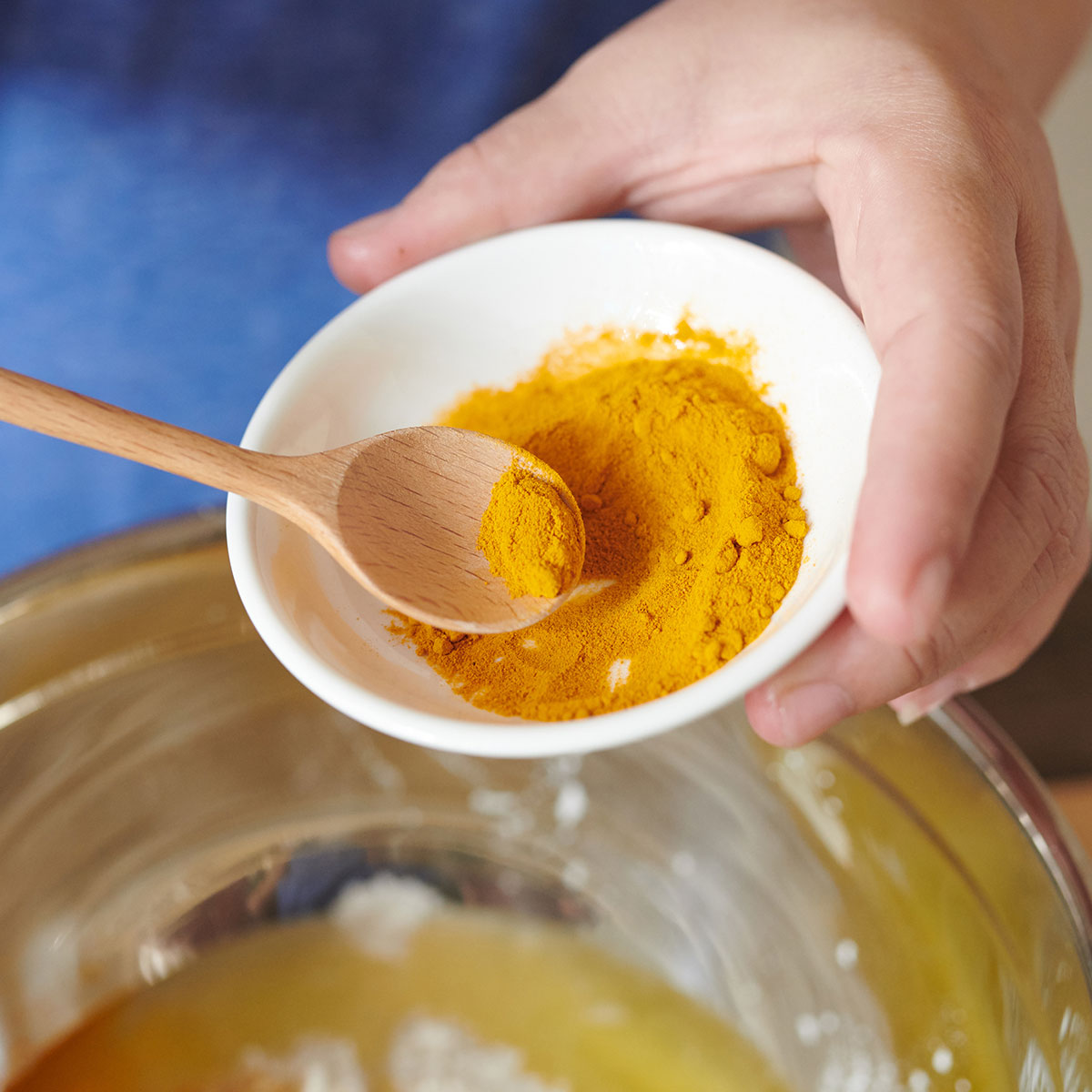 woman scooping ground turmeric into bowl