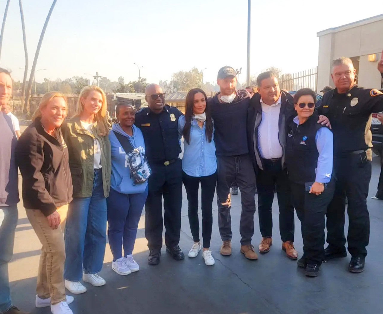 Prince Harry and Meghan Markle posing at Rose Bowl with LA fire helpers