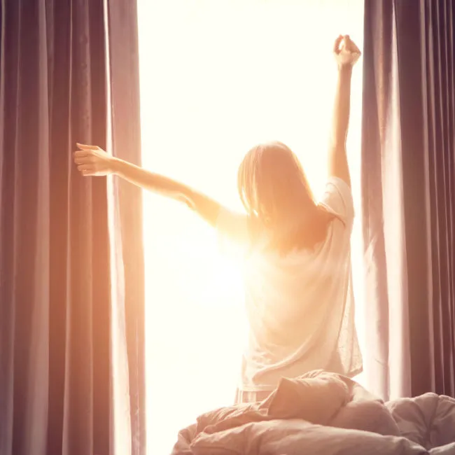 woman stretching in front of sunny window