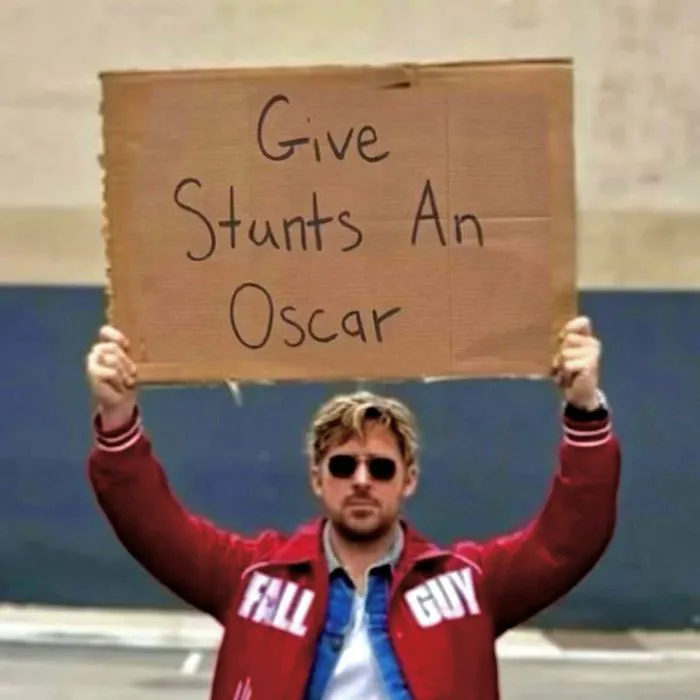 "Ryan Gosling holding a sign advocating for stunt recognition"