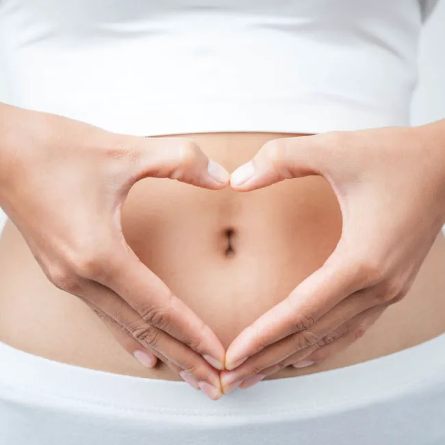 woman making heart with hand over stomach