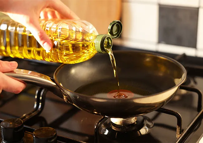 Pouring vegetable oil into a frying pan for cooking.
