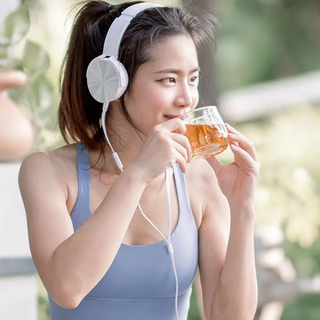 woman sipping tea outside with headphones on