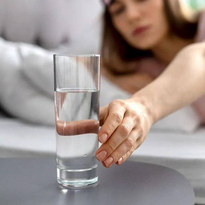 "Woman reaching for a glass of water first thing in the morning"