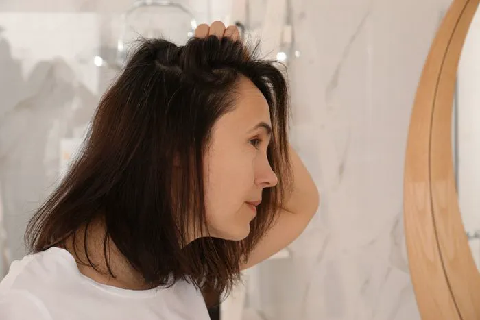 "Woman with hair loss looking in the mirror"