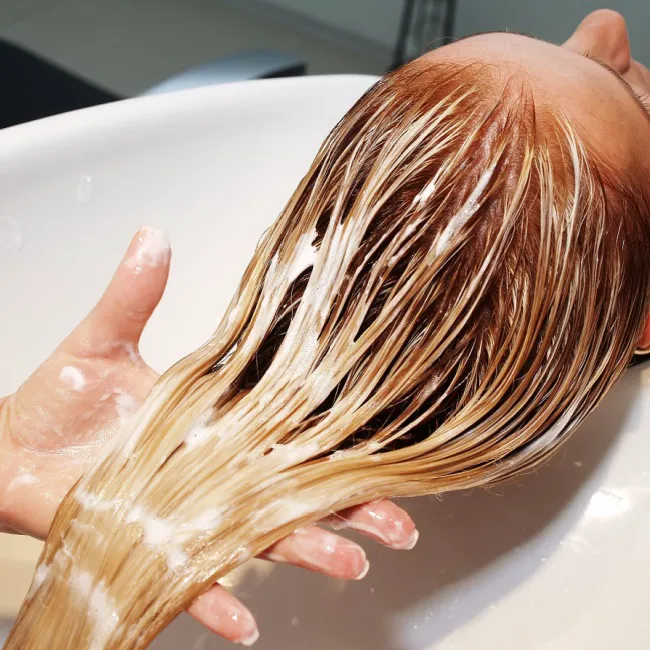 Woman with thinning hair touching her scalp