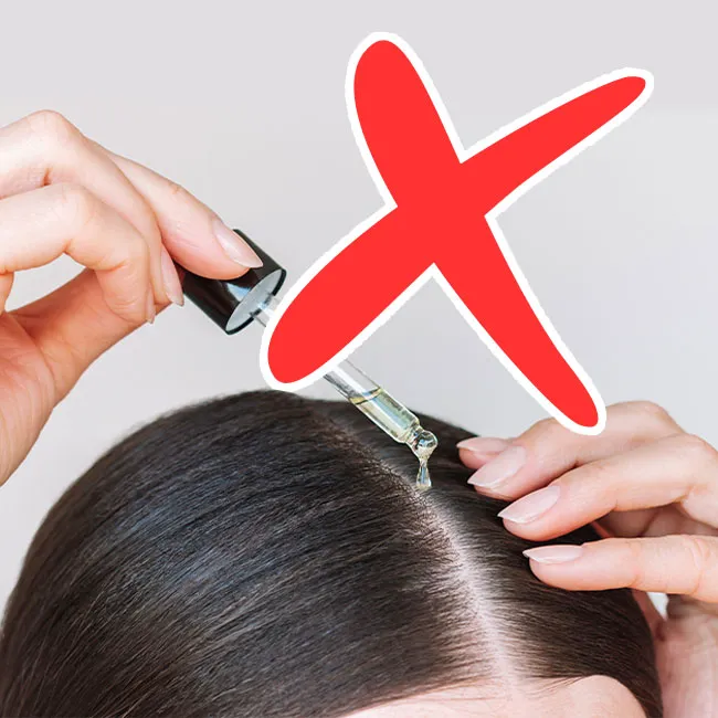 Woman applying hair oil to her scalp