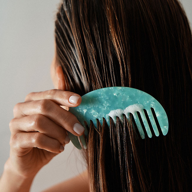 Woman combing product through her hair