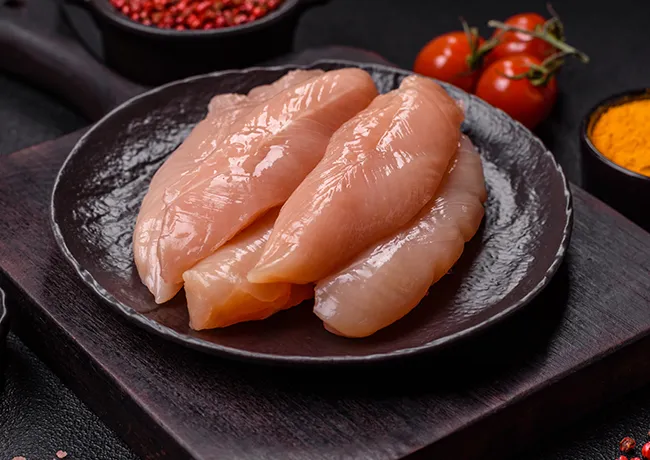"Raw chicken breast strips on a plate"