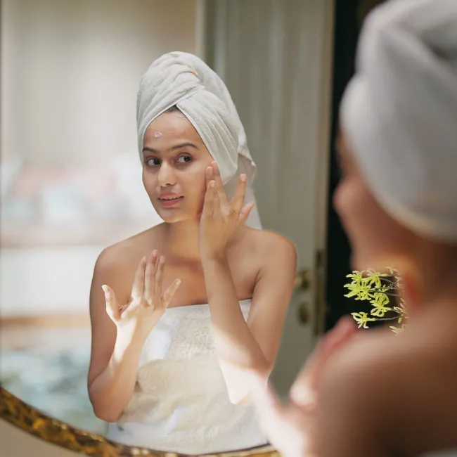"Woman applying moisturizer to her face"