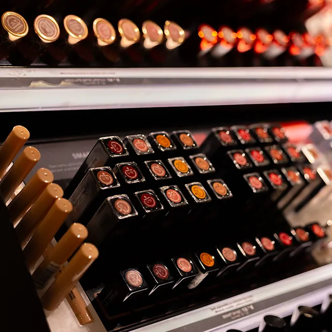 "Display of various lipstick and lip gloss products on shelves"