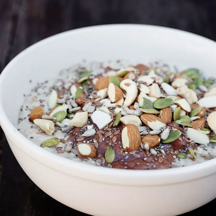 "Bowl of oatmeal topped with nuts and seeds"
