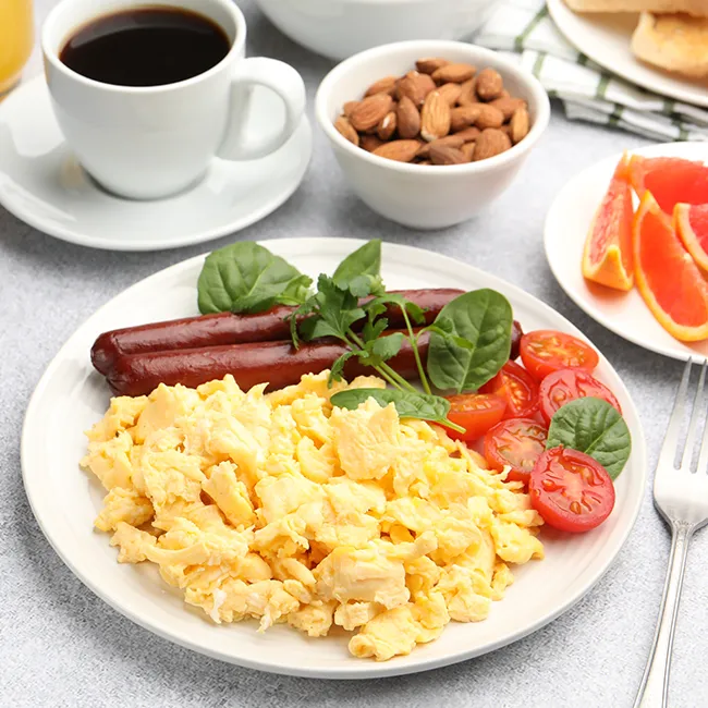 Scrambled eggs with sausage and tomatoes on a plate.