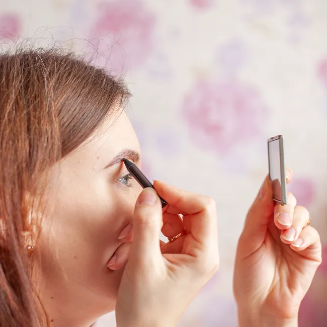 "Woman filling in her eyebrows for a polished look"