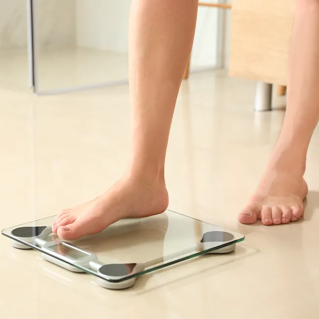 Woman stepping onto a scale for weight tracking.