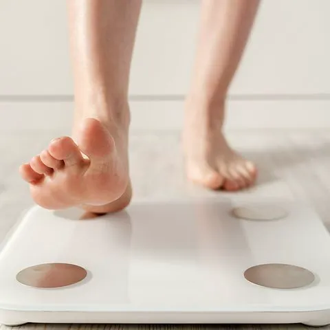 "Woman stepping on a scale to monitor her weight"