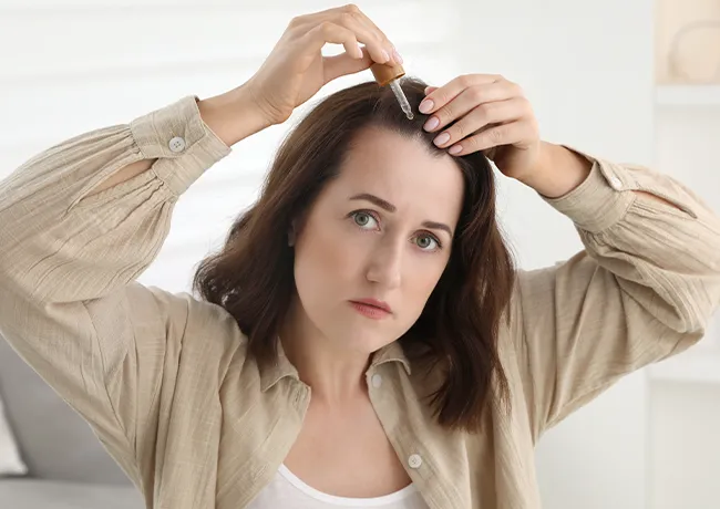 Woman applying hair serum for added shine and nourishment.