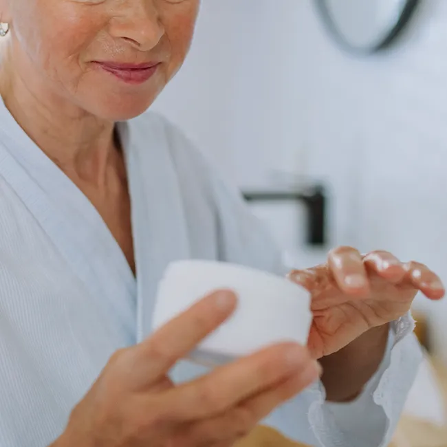 "Woman applying neck cream to improve skin texture"