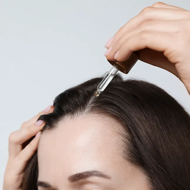 "Woman applying serum on her scalp for hair health"