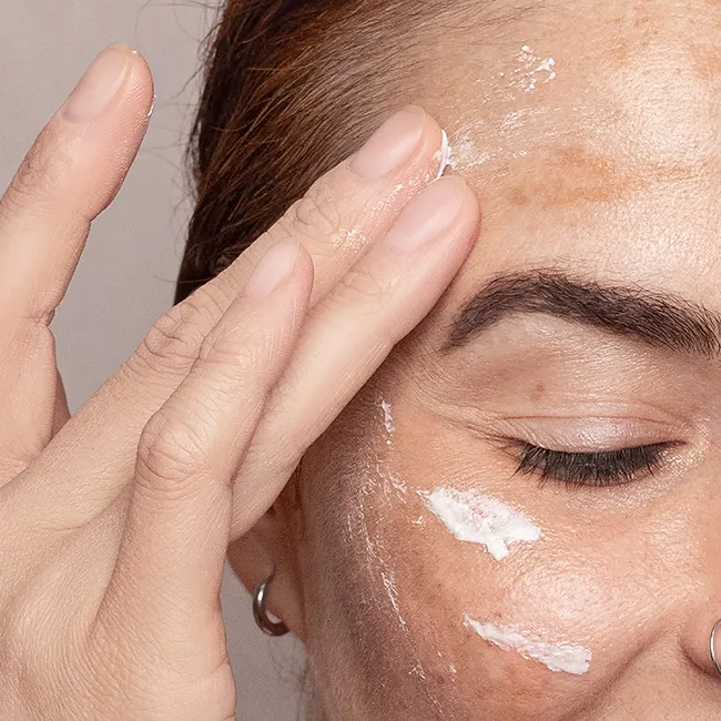 "Woman using sunscreen on age spots for skin protection"
