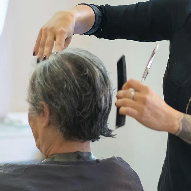 Woman with grey hair receiving a stylish haircut.