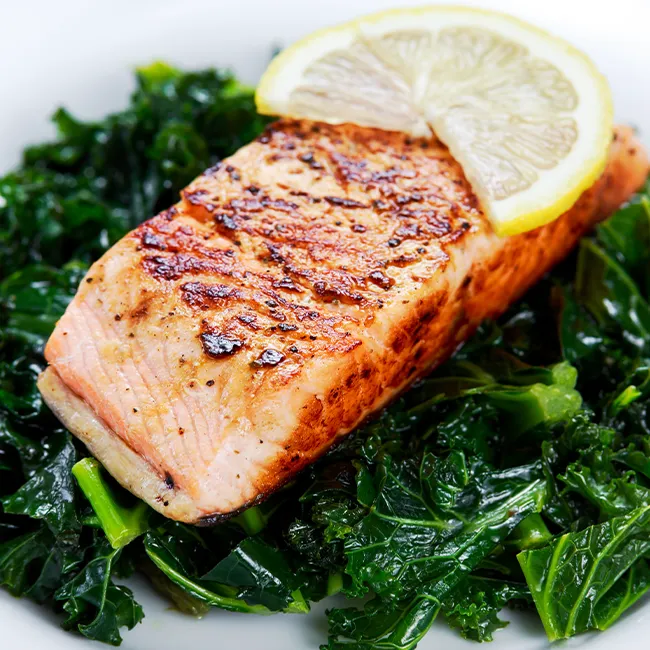 "Pan-fried salmon served with kale on a plate"