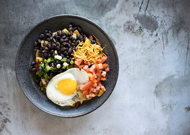 "Breakfast bowl with eggs, greens, beans, and salsa"
